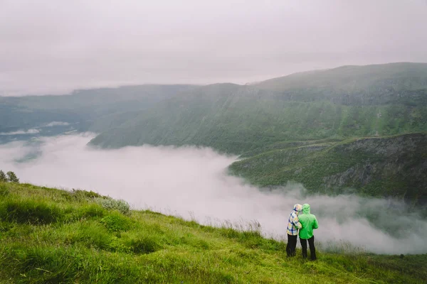 在挪威徒步旅行。浪漫的一对游客在悬崖边上欣赏美丽的风景。在观景台拥抱的背面视图,全景。一起旅行,冒险 — 图库照片
