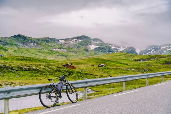 Fahrrad mit aktiver Ausrüstung in den norwegischen Bergen. Fahrrad am Berg. Fahrrad, das auf der Straße gegen Berge geparkt war. Fahrradtourismus in den norwegischen Bergen, Skandinavien und Europa — kostenloses Stockfoto