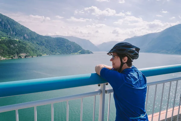 İskandinavya'da dağ bisikleti teması. Norveç'te Bisikletli kask lı ve spor giyimli insan turist, Norveç'in güneybatısındaki Hardanger Fjord'a atılan Hardanger Köprüsü asma köprüsünde — Stok fotoğraf