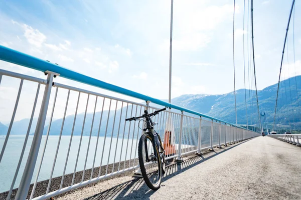 Tema de ciclismo de montaña en Escandinavia. turista humano en casco y ropa deportiva en bicicleta en Noruega en el puente colgante Hardanger Bridge lanzado a través del fiordo Hardanger en el suroeste de Noruega — Foto de Stock