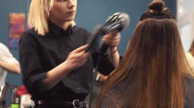 Kuaförde mutlu kadının portresi. Profesyonel saç şekillendirme konsepti. Kuaför saç kurutma makinesi ve fırça kullanarak kız uzun saç kurutma. Fön Kurutma Makinesi ile Kurutma