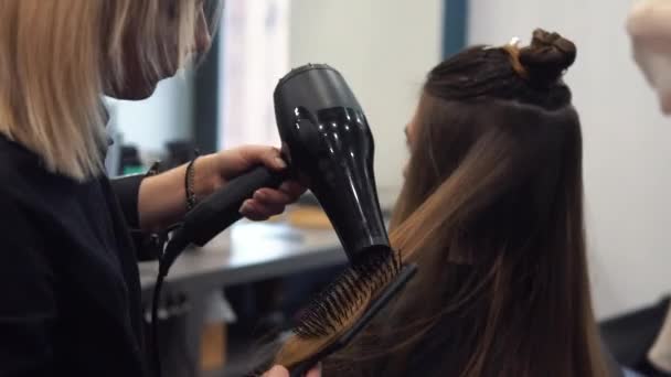 Porträtt av lycklig kvinna på frisörsalongen. Professionellt hårstyling-koncept. Frisör torkning flicka långt hår med hårtork och borste. Torkning med fön — Stockvideo