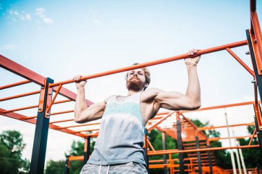 güçlü atlet yatay çubuk üzerinde pull-up yapıyor. Kaslı adam parkta yatay barda yukarı çekiyor. Egzersiz sırasında Jimnastik Bar. eğitim strongmanoutdoor park spor salonu. Man Egzersiz spor salonu Açık yapıyor