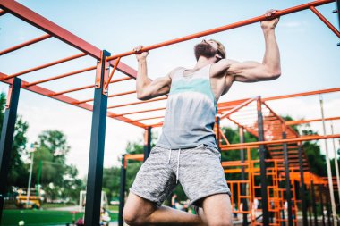 güçlü atlet yatay çubuk üzerinde pull-up yapıyor. Kaslı adam parkta yatay barda yukarı çekiyor. Egzersiz sırasında Jimnastik Bar. eğitim strongmanoutdoor park spor salonu. Man Egzersiz spor salonu Açık yapıyor