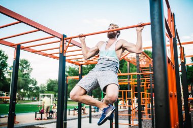 güçlü atlet yatay çubuk üzerinde pull-up yapıyor. Kaslı adam parkta yatay barda yukarı çekiyor. Egzersiz sırasında Jimnastik Bar. eğitim strongmanoutdoor park spor salonu. Man Egzersiz spor salonu Açık yapıyor