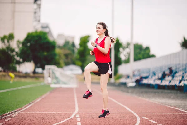 Sportovkyně připravuje nohy na kardio cvičení. Fitness běžec dělá zahřívací rutinu. žena běžec zahřívá venku. atlet protahování a zahřívání na běžecké dráze na stadionu — Stock fotografie