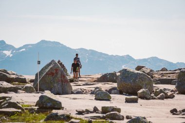 26 Temmuz 2019. Trolltunga üzerinde Norveç turistik rota. İnsanlar turistler thetrolltunga ince güneşli havalarda Norveç dağlarında yürüyüş gidin. Yürüyüş sırt çantası teması
