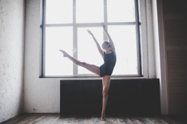 Plastiklik ince kadın pencere yakınında dans. Profesyonel dansçı dans keyfini çıkarın. Lady Dancer Eğitim Modern Bale Sınıfta. Çağdaş dans sanatçısı. Gün ışığı, siluet güzel vücut. Dans teması