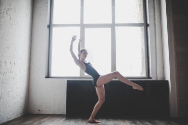 Plastiklik ince kadın pencere yakınında dans. Profesyonel dansçı dans keyfini çıkarın. Lady Dancer Eğitim Modern Bale Sınıfta. Çağdaş dans sanatçısı. Gün ışığı, siluet güzel vücut. Dans teması