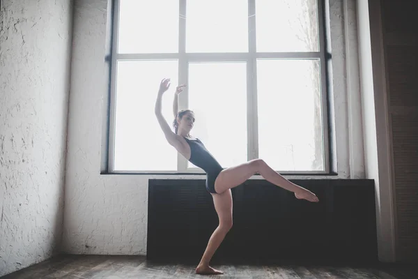 Plasticiteit slanke vrouw dansen in de buurt van venster. Professionele danser geniet van dans. Lady Dancer traint modern ballet in de klas. Hedendaagse dans performer. Daglicht, silhouet mooi lichaam. Dans thema — Stockfoto