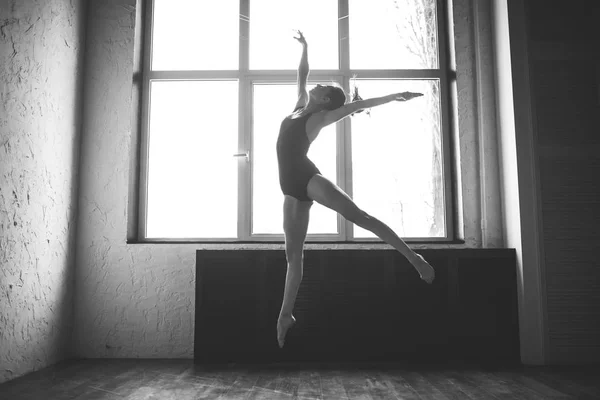 Пластиковая стройная женщина танцует у окна. Профессиональный танцор любит танцевать. Леди-танцовщица готовит современный балет в классе. Артист современного танца. Дневной свет, силуэт красивого тела. Тема танца — стоковое фото
