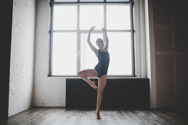 Plasticiteit slanke vrouw dansen in de buurt van venster. Professionele danser geniet van dans. Lady Dancer traint modern ballet in de klas. Hedendaagse dans performer. Daglicht, silhouet mooi lichaam. Dans thema — Stockfoto