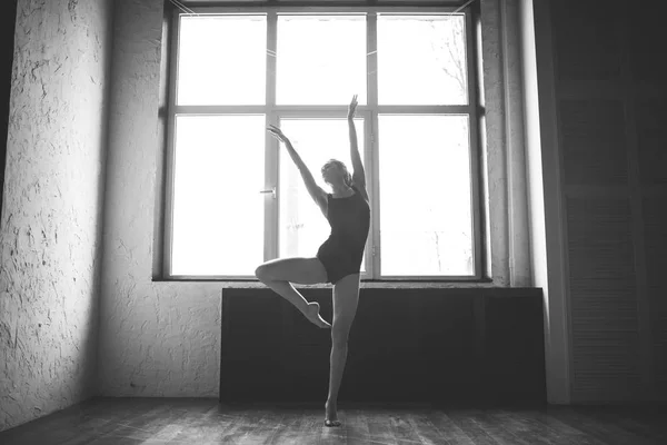 Plasticità donna magra ballare vicino alla finestra. La ballerina professionista ama la danza. Ballerina che allena danza moderna in classe. Artista di danza contemporanea. Luce del giorno, silhouette bellissimo corpo. Tema della danza — Foto Stock