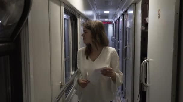 El tema del transporte terrestre y los viajes. Hermosa joven mujer caucásica en la estación de tren esperando la salida del tren dentro del interior del coche. Utiliza tecnología de telefonía móvil — Vídeo de stock