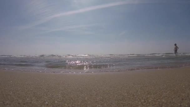 5 de outubro de 2017. Espanha. Barcelona. Menino silhueta infantil correndo joga alegria felicidade na água do mar, no mar no verão praia de Espanha barcelona em um parque de campismo perto do aeroporto — Vídeo de Stock