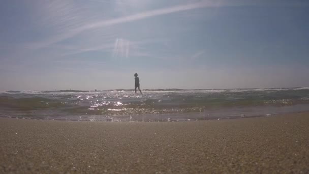 Október 5, 2017. Spanyolország. Barcelona. Gyermek sziluett fiú fut játszik öröm boldogságot tengervízben, a tenger nyáron Barcelona Spanyolország strand egy kemping közelében, a repülőtér — Stock videók