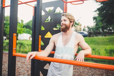 Portre genç sakallı adam kamu spor zemin üzerinde duran ve paralel barlar üzerinde eğitim. Yakışıklı egzersiz atleti. Sakallı portre sportif adam, eğitimden sonra dinlenme. Yaz egzersiz açık havada