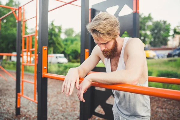 Portrait of Tired Athlete at Gym. Tired man hanging from the bar. Exhausted athlete working out in gym. Time to rest. Long workout is over. Muscular guy after workout. sportsman taking a break — Stock Photo, Image