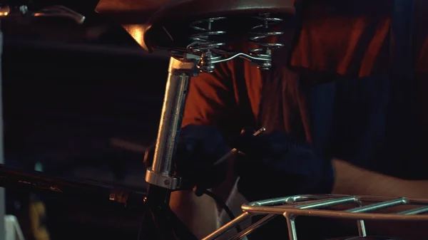 Thema Reparatur von Geschäftsfahrrädern. ein junger kaukasischer brünetter Mann mit Schutzbrille, Handschuhen und Schürze repariert und justiert das Fahrrad in der Werkstatt — Stockfoto