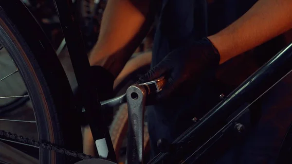 Тема малый бизнес ремонт велосипедов. Молодой кавказский брюнетка мужчина в защитных очках, перчатках и фартуке использует ручной ремонт и регулировку ручки и педали системы велосипед в гаражной мастерской — стоковое фото