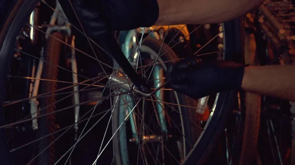 Tema små företag cykel reparation. En ung kaukasisk brunett man bär skyddsglasögon, handskar och ett förkläde använder en handverktyg för att reparera och installera cykelns Modguards i ett garage verkstad — Stockfoto