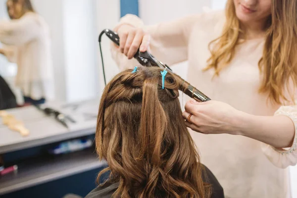 Piękno, koncepcja fryzury, szczęśliwa młoda kobieta i fryzjer z żelaza do włosów fryzurę w salonie fryzjerskim. Kobieta o włosy stylizowane fryzjer. Wygładza włosy curling. Stylista za pomocą narzędzia do modelowania — Zdjęcie stockowe