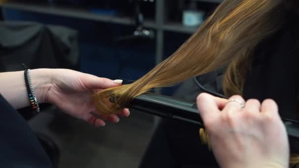 Schoonheid, kapsel concept, gelukkige jonge vrouw en kapper met strijkijzer maken kapsel in de kapsalon. Vrouw met haar gestileerde kapper. Verzacht Hair Curling. Stylist Gereedschap voor modellering gebruiken — Stockvideo