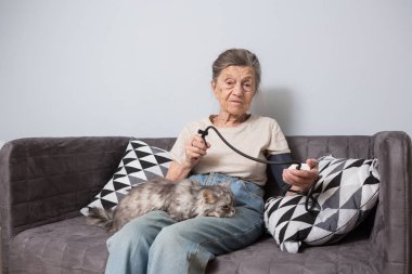 Konu çok eski kişi ve sağlık sorunları var. Bir üst düzey beyaz bir kadın, 90 yaşında bir çocuk, kırışıklık ve gri saç ile ana sayfa ile evde beslenen hayvan kedi koltukta oturur ve tonometer kullanır. Yüksek tansiyon baş ağrısı