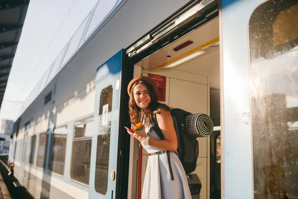Жінка шукає потяг. Жінка залізничного вокзалу. Молода щаслива жінка витягує обличчя до вокзалу, шукаючи когось залізничного вокзалу. Подорожі. Портретна дівчина, що стоїть на дверях поїзда, коли прибуває — стокове фото