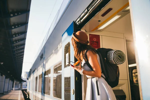 Жінка шукає потяг. Жінка залізничного вокзалу. Молода щаслива жінка витягує обличчя до вокзалу, шукаючи когось залізничного вокзалу. Подорожі. Портретна дівчина, що стоїть на дверях поїзда, коли прибуває — стокове фото