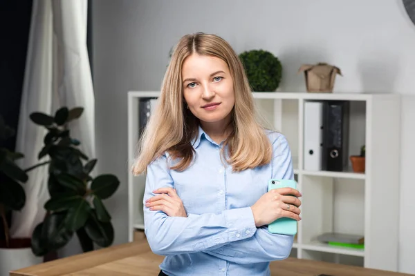 Retrato de mulher de negócios com telefone celular em pé no escritório. jovem mulher de negócios caucasiana segurando telefone celular no escritório. mulher de negócios usando telefone. Executivo de negócios conversando no celular — Fotografia de Stock