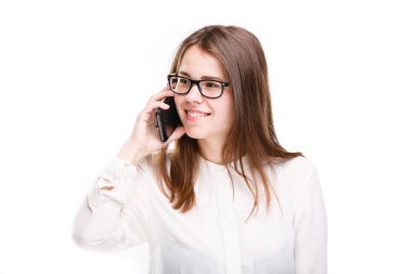 Cep telefonuyla konuşan gözlüklü gülümseyen iş kadını. Beyaz izole arka plan üzerinde beyaz gömlek güzel genç kız cep telefonu konuşuyor. Cep telefonu olan gömlekli kadın. Kopya alanı. Boş