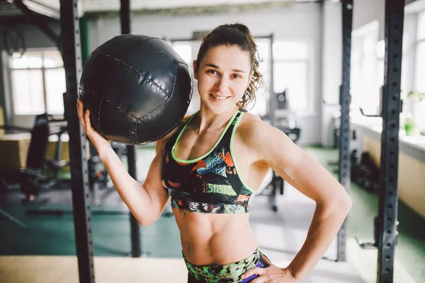 Hermosa chica caucásica sosteniendo una pelota en el gimnasio. Vestido con top y pantalones cortos — Foto de Stock