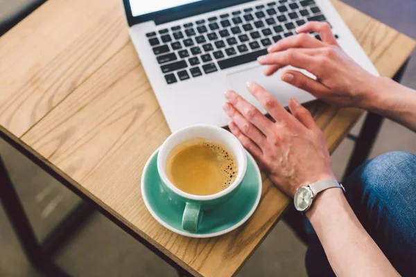 Primeros planos de la mujer de negocios manos utilizando el ordenador portátil con café taza. Manos de mujer Teclado de computadora en la cafetería. smartphone y taza caliente Cappuccino en la mesa. Concepto de estilo de vida de la gente. Tema independiente — Foto de Stock