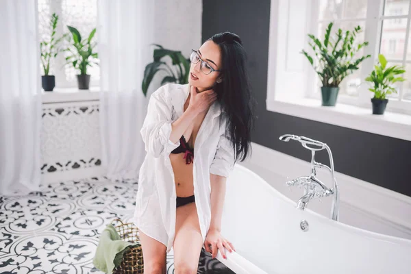 Woman In Bathroom. beautiful girl on bathtub in underwear. Sex woman taking relaxing bath in jacuzzi. Beautiful sexy lady elegant white shirt in bathroom. Fashion portrait model on bath indoors — Stock Photo, Image