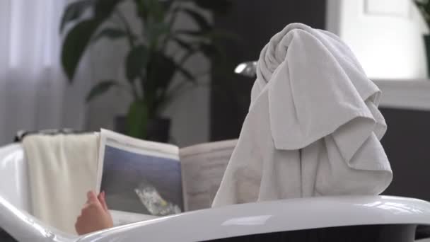 Jeune femme caucasienne avec serviette sur la tête et lunettes de soleil obtenir un traitement spa dans un salon de beauté, à l'intérieur d'une pièce intérieure. Détente dans la salle de bain en lin. Le concept de soin du corps et de relaxation — Video