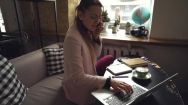 Telefonda konuşan mutlu bir iş kadını. Kafedeki kadın, cep telefonu kullan, defter üzerinde çalış. Kafeteryadaki kadın telefon ve laptop kullanıyor, kahve içiyor. Güzel İş Kadını Mola Çalışıyor
