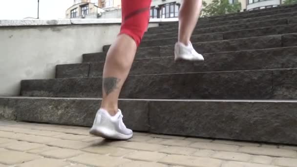 Deporte temático y un estilo de vida saludable. Joven atleta con tatuaje hace cardio corriendo por las escaleras. Entrenamiento de resistencia y entrenamiento de pérdida de peso urbano — Vídeos de Stock