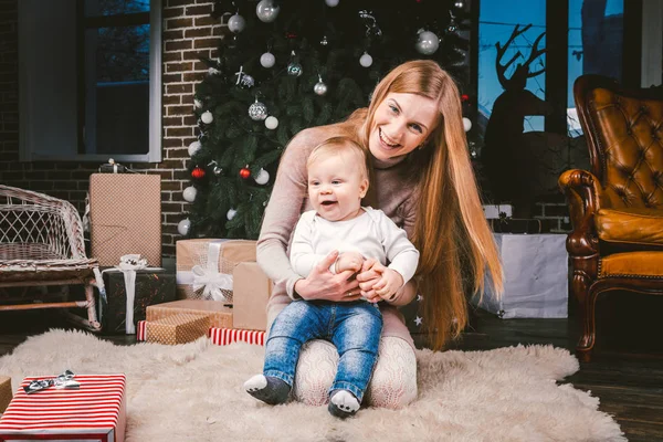 Joven madre e hijo jugando cerca del árbol de Navidad. joven madre e hijo jugando cerca del árbol de Navidad. Noche de Navidad familiar. Mamá e hijo en piso alfombra peluda bajo el árbol de Navidad — Foto de Stock