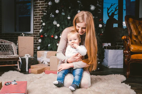 Joven madre e hijo jugando cerca del árbol de Navidad. joven madre e hijo jugando cerca del árbol de Navidad. Noche de Navidad familiar. Mamá e hijo en piso alfombra peluda bajo el árbol de Navidad — Foto de Stock