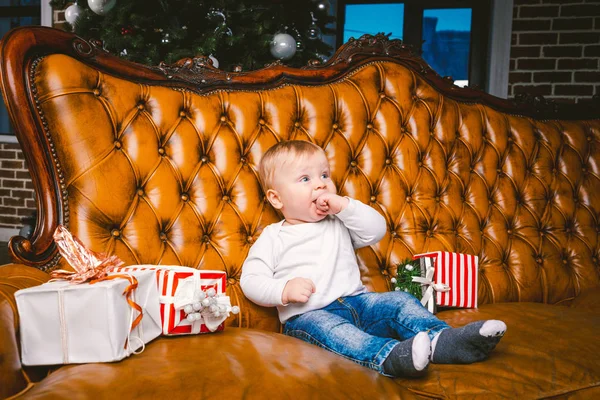 Feliz niño sonriente con caja de regalo de Navidad. Hermoso bebé, se sienta en asofa con regalo. Niño sentado junto a un montón de regalos de Navidad. concepto de regalo de Navidad — Foto de Stock