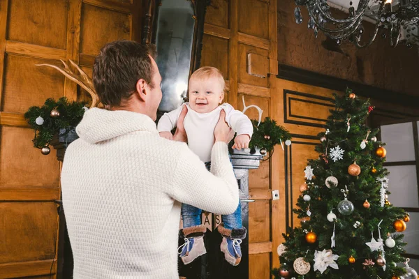 El hombre y el bebé lindo están listos para celebrar el año nuevo. Feliz padre e hijo hijo cerca del árbol de Navidad y chimenea en la noche de Navidad. tema vacaciones familiares Año Nuevo y Navidad — Foto de Stock