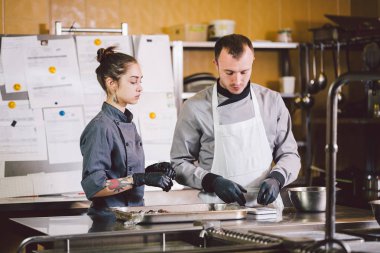 Neşeli deneyimli erkek ve kadın personel. Meslek hazırlama şekerleme ürünleri. Kafkas adam ve kadın iki çalışan meslektaşım takım çalışması pasta şefi. Tema pişirme çikolata trüf