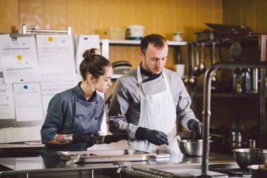 Neşeli deneyimli erkek ve kadın personel. Meslek hazırlama şekerleme ürünleri. Kafkas adam ve kadın iki çalışan meslektaşım takım çalışması pasta şefi. Tema pişirme çikolata trüf
