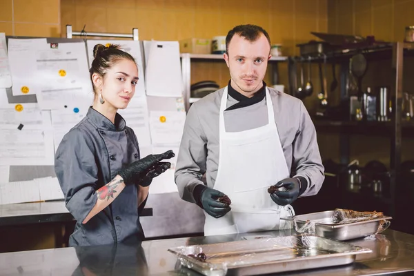 Cheerful Experienced Man And Woman Staff. Profession preparation confectionery products. Caucasian man and woman two employees colleague teamwork pastry chef. Theme cooking chocolates truffle — Stock Photo, Image