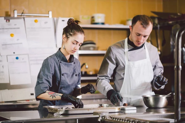 Cheerful Experienced Man And Woman Staff. Profession preparation confectionery products. Caucasian man and woman two employees colleague teamwork pastry chef. Theme cooking chocolates truffle — Stock Photo, Image