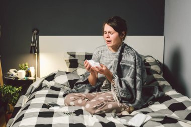 Burnu akan hasta bir kadın, yatakta oturuyor. Kadın kendini iyi hissetmiyor ve hapşırıyor. Elinde doku tutan bir kadın, grip belirtileri. Sağlık hizmeti tıbbi konsepti. Soğuk ve soğuk algınlığı mevsimi. Alerjisi olan kadın.