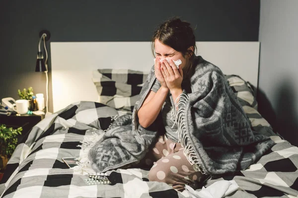 Mulher doente com corrimento nasal, sentada na cama. mulher sentindo-se mal e espirrar quarto. Mulher segurando tecido, sintomas de gripe. Conceito médico de saúde. Temporada fria e gripe. mulher com sintomas alérgicos — Fotografia de Stock