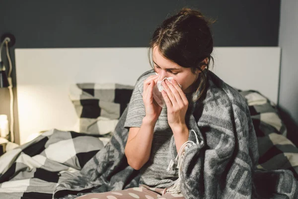 Wanita sakit dengan hidung beringus, duduk di tempat tidur. Wanita merasa tidak enak badan dan bersin kamar tidur. Wanita yang memegang jaringan, gejala flu. Konsep kesehatan medis kesehatan. Musim Dingin dan Flu. Wanita dengan gejala alergi — Stok Foto