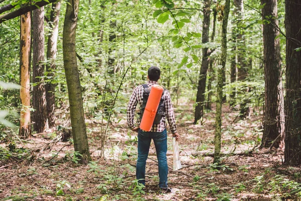 Hombre con mochila y mapa en busca de direcciones en la zona salvaje. Turista con mochila usando mapa en bosque. concepto turismo vacaciones. Caminante. Hombre viajero perdido caminando en el bosque mirando el mapa — Foto de Stock